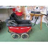 A painted metal Victorian dolls pram with leather canopy and interior