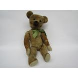 An early 20th Century straw filled jointed bear with black boot button eyes and hump back,
