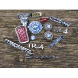 A box of mixed car badges including Triumph, Saab and Fiat