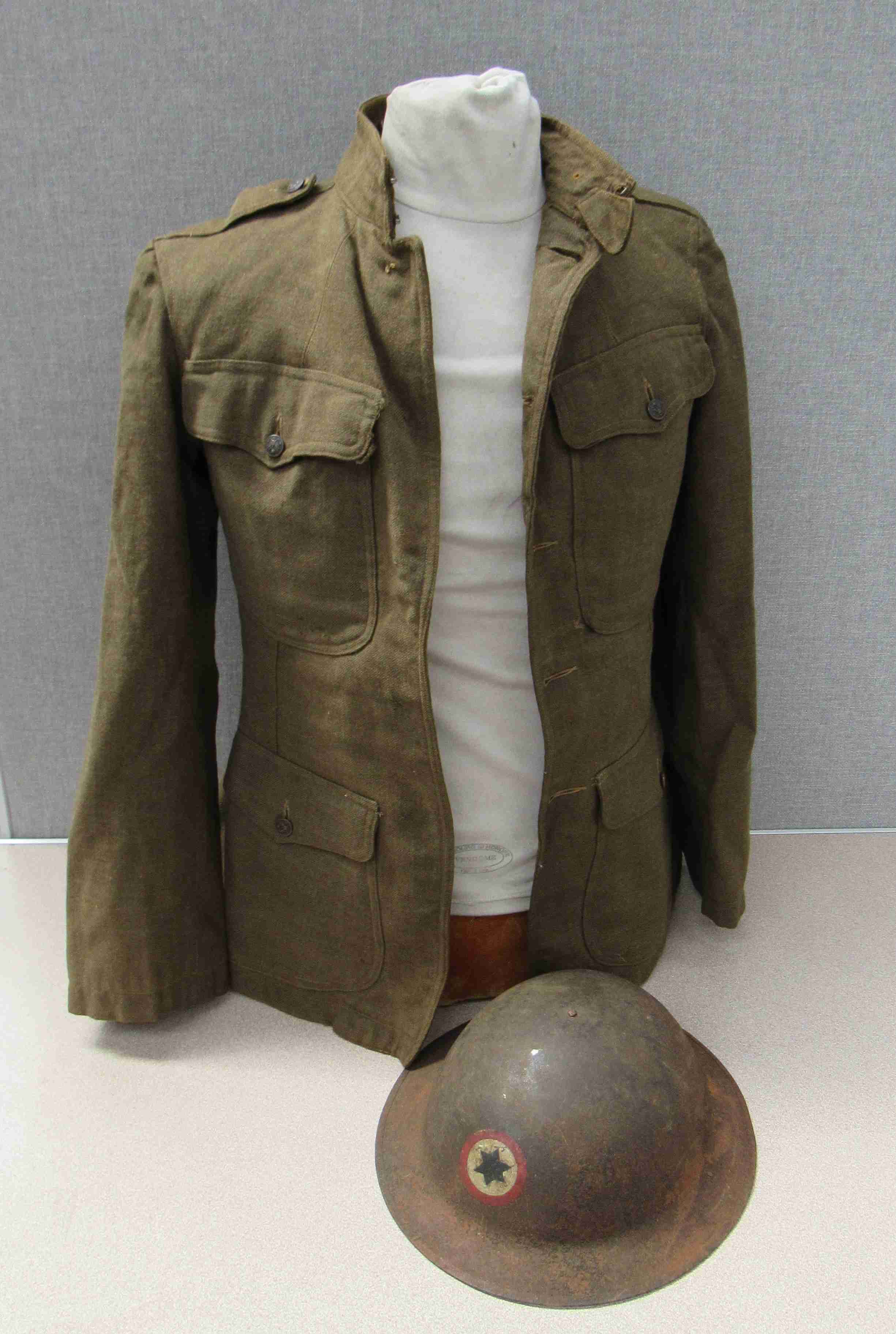 A WWI US soldier's service jacket with US Army insignia and US Army Brodie helmet with division