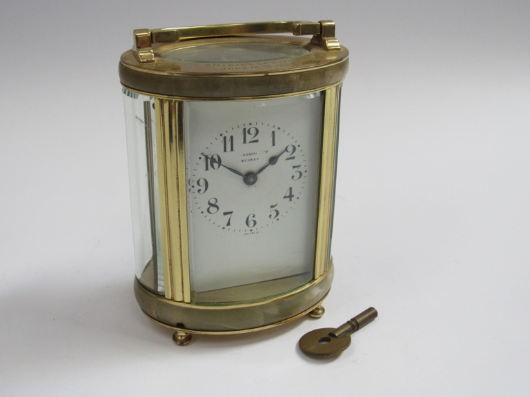 An early 20th Century brass and onyx cased French single train carriage timepiece of oval form.