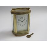 An early 20th Century brass and onyx cased French single train carriage timepiece of oval form.