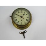 An early to mid 20th Century Smiths Astral brass cased ships clock with key, Roman dial with red
