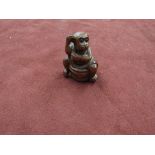 An Oriental carved wood netsuke of a monkey washing