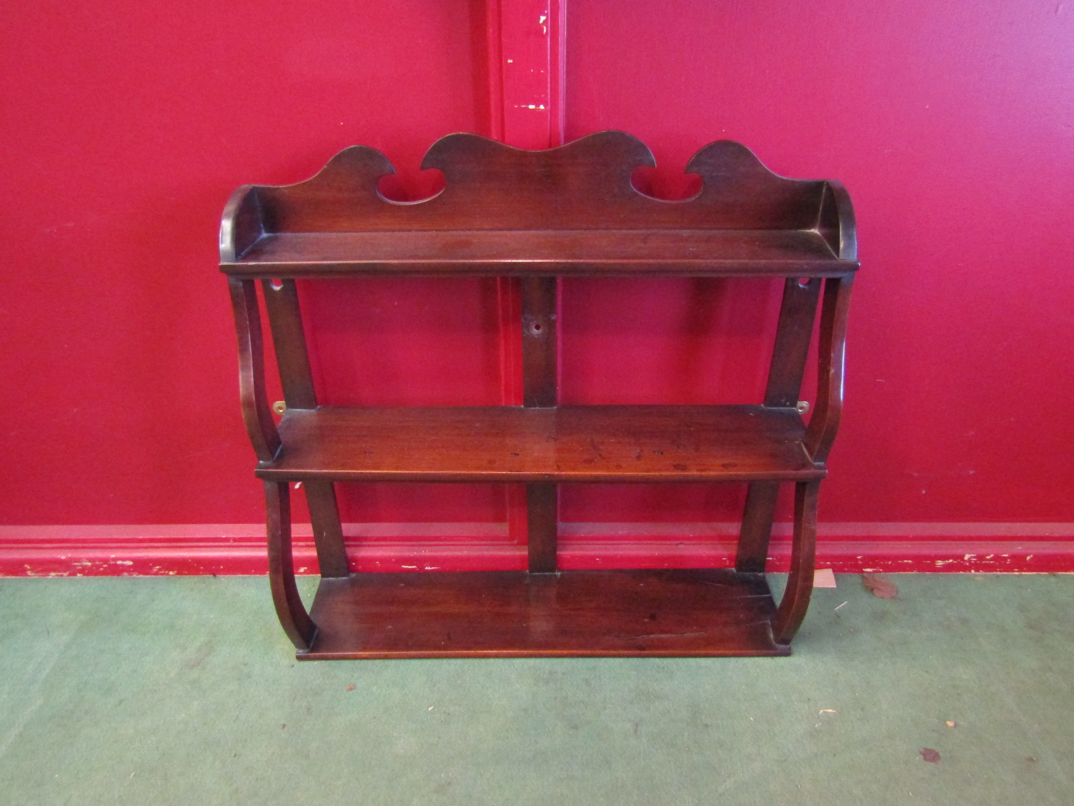 A 19th Century mahogany three tier wall hanging shelf with wavy supports and raised gallery back