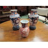 A pair of late 19th/early 20th Century Imari fluted baluster vases (a/f) with wooden bases,