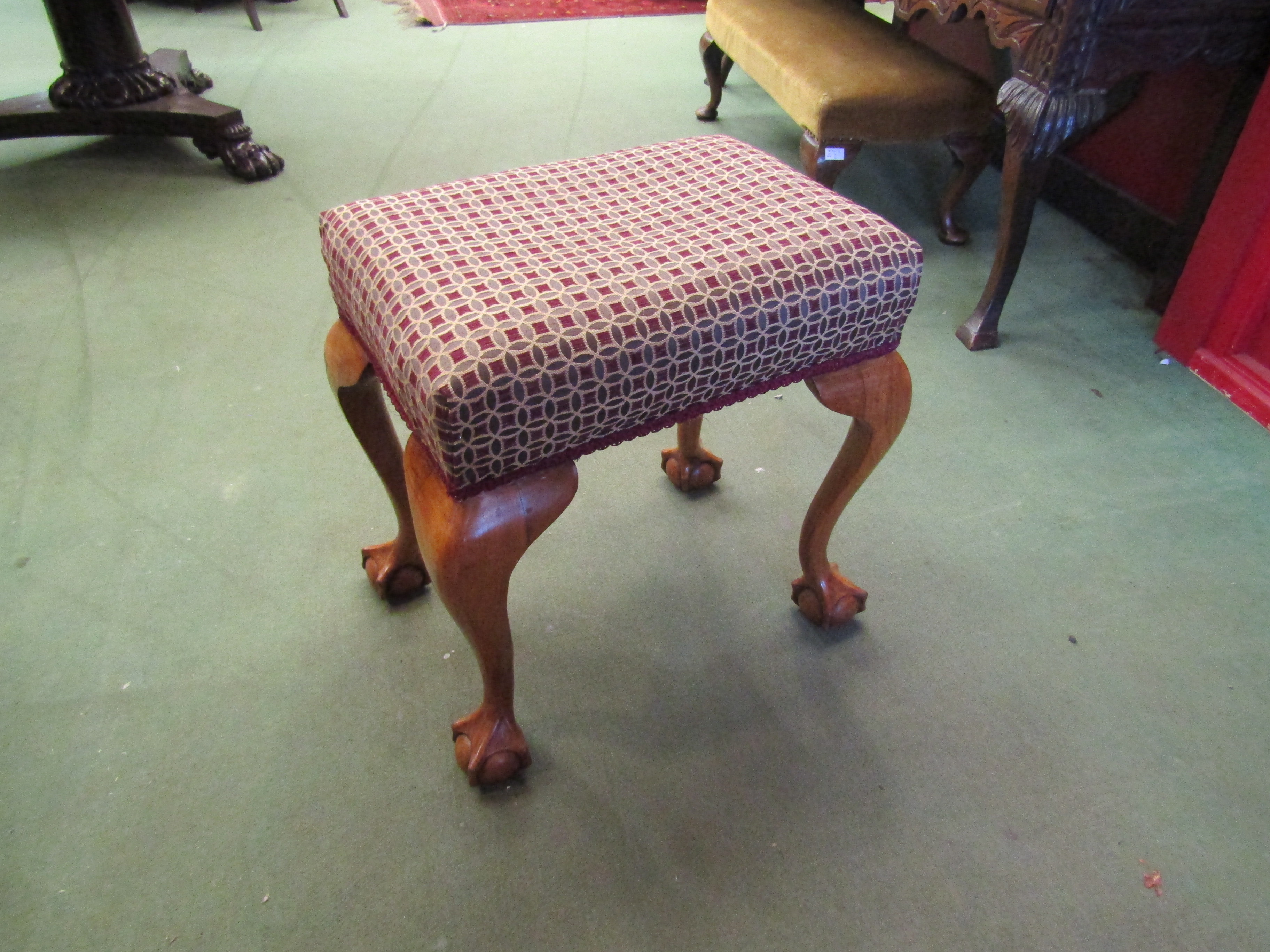 A 19th Century walnut stool the upholstered seat over ball in claw cabriole legs,