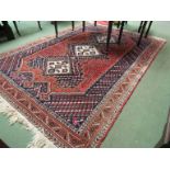 A 20th Century Iranian wool rug worked in blue and cream on a red ground