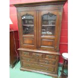 An 18th Century style oak cabinet on chest the two glazed doors with key over a bank of six drawers