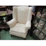 Circa 1930 a wingback fireside armchair with loose cover,