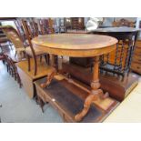 A Victorian burr walnut oval top writing table with worn leather top,