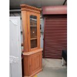 A modern pine corner cabinet with a glass top door and a cupboard