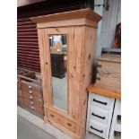 An Edwardian pine wardrobe with mirrored door over single drawer base