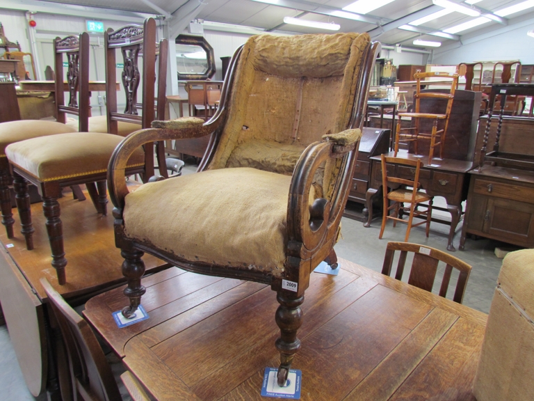 A 19th Century scroll arm armchair on turned legs to castors for re-upholstery