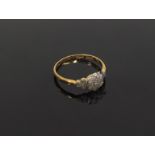 An illusion set diamond daisy ring with three small diamonds to each side, stamped 18ct. Plat.