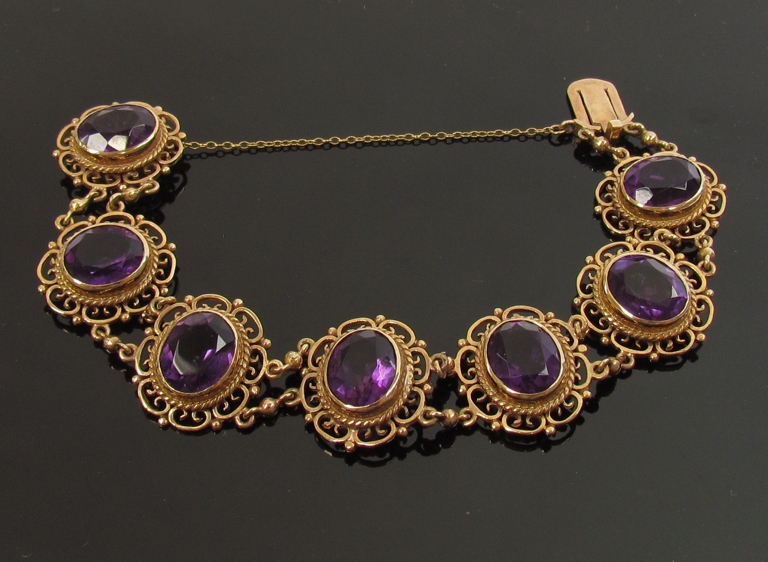 A 9ct gold bracelet with seven decorative open panels set with oval amethysts, 12mm x 10mm,