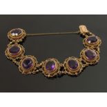 A 9ct gold bracelet with seven decorative open panels set with oval amethysts, 12mm x 10mm,