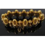 A gold bracelet with ovoid and scrolled links, unmarked tested as 18ct gold,