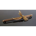 A gold bar brooch surmounted with a seed pearl studded dragonfly, pale blue stone to centre,