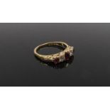 An 18ct gold garnet and diamond ring the centre garnet flanked by a diamond and garnet in turn .