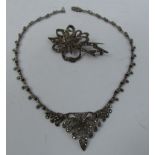 A marcasite set necklace stamped silver (10 small marcasites missing) and a floral form marcasite