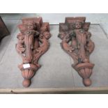 A pair of terracotta wall brackets in the form of cherubs. 52cm tall.