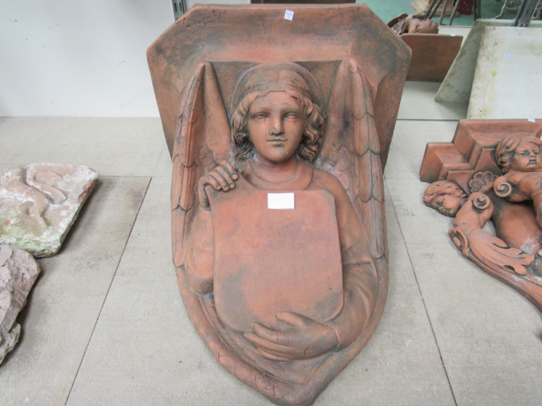 A terracotta wall bracket in the form of a lady holding a shield. Approximately 46cm tall.