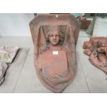 A terracotta wall bracket in the form of a lady holding a shield. Approximately 46cm tall.
