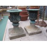 A pair of highly decorative small cast urns, set in composition bases.