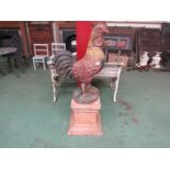 A cast iron cockerel on a terracotta coloured plinth. Cockerel 86cmtall. Plinth 46cm tall.