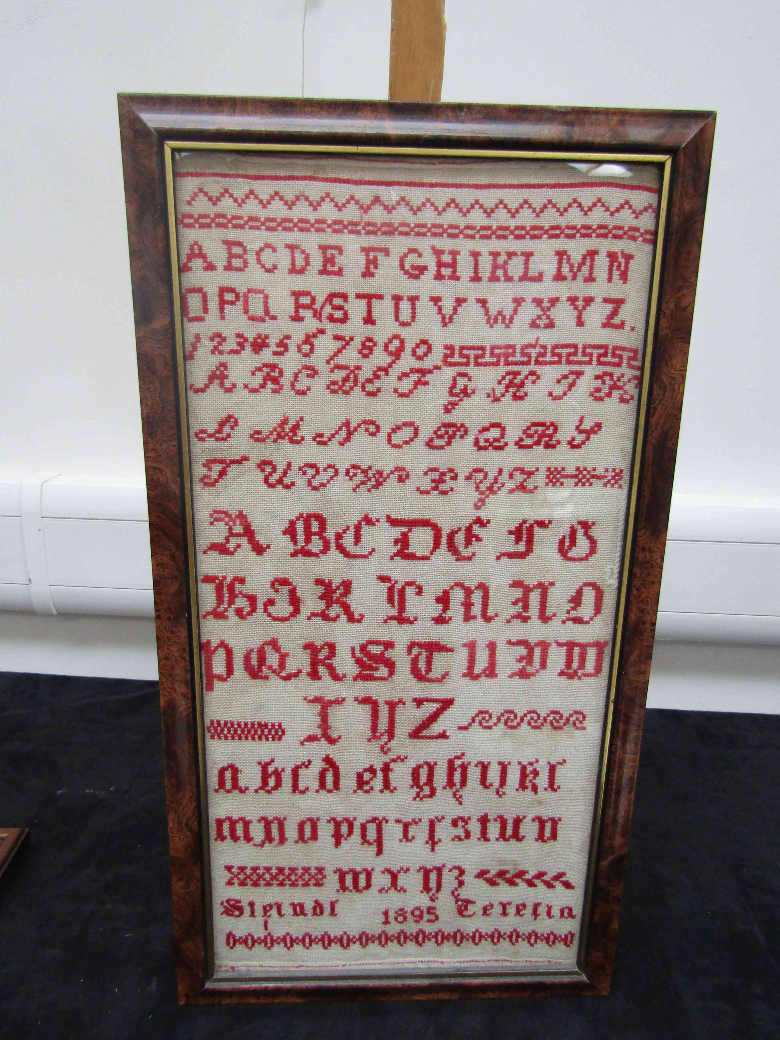 A late Victorian schoolroom sampler worked in red thread cross-stitch on a narrow-weave linen