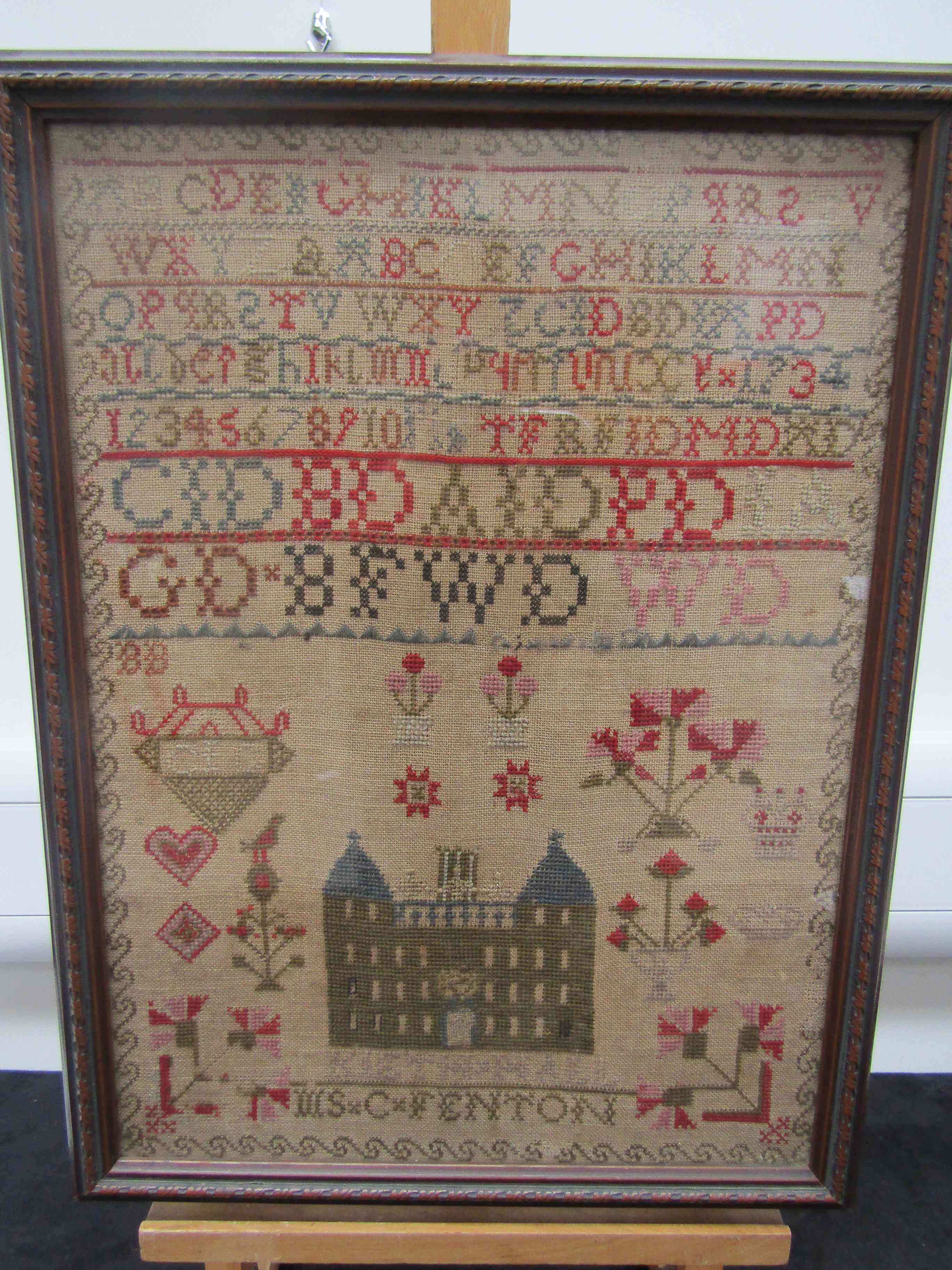 A Victorian schoolroom sampler worked in cross-stitch in coloured threads on a canvas ground with