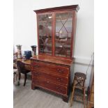 A Georgian mahogany glazed two door bookcase cabinet above a three drawer base with brushing slide.