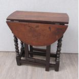 An 18th Century oak gate leg oval top occasional table the rising leaves over turned legs joined by
