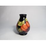 A Moorcroft vase with apricots and berry design, marked "T" to base, 14cm tall,