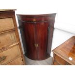 A George III mahogany bow-front wall-hanging corner cupboard with shell patere inlay,
