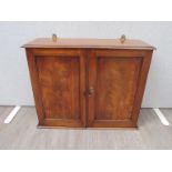 Circa 1840 a flame mahogany wall hanging two door cupboard with key opening to reveal a three