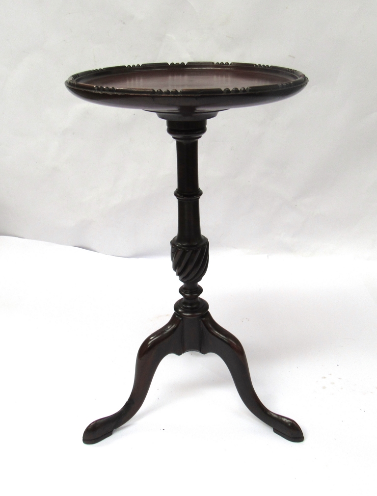 An Edwardian mahogany dish top wine table with shaped edge over a turned and wrythen coloumn on