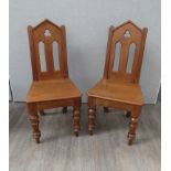 A pair of late Victorian Arts & Crafts oak hall chairs the Cathedral arch top back rest and