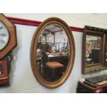 A gilt oval wall mirror with bevelled edge,