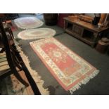 A Chinese washed oval pink and cream ground rug and two hand tufted wool rugs