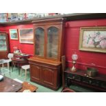 A Victorian oak twin glazed door bookcase above a single drawer/ two door cupboard base with arched