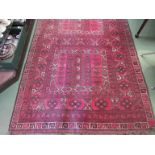 A red ground geometric design rug with multiple borders and tasselled ends,