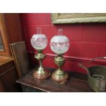 A near pair of brass oil lamps with hardwood bases and frosted glass shades