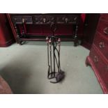 A wrought iron four piece companion set on stand