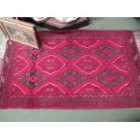 A red ground Eastern rug with geometric pattern and tasselled ends,