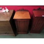 A late Victorian walnut bedside cupboard the carved raised back over a single door on a plinth base,