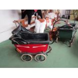 A painted metal Victorian dolls pram with leather canopy and interior