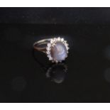 A platinum ring set with a cabochon stone framed by diamonds, unmarked. Size O, 3.