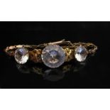 A gold bracelet set with three zircons linked by delicate foliate panels, unmarked, 10.